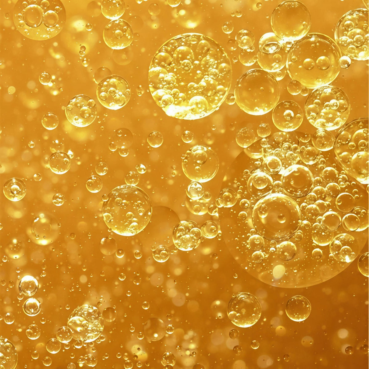 Makroaufnahme einer goldfarbenen Zwei-Phasen-Flüssigkeit mit feinen Öl- und Wasserbläschen.