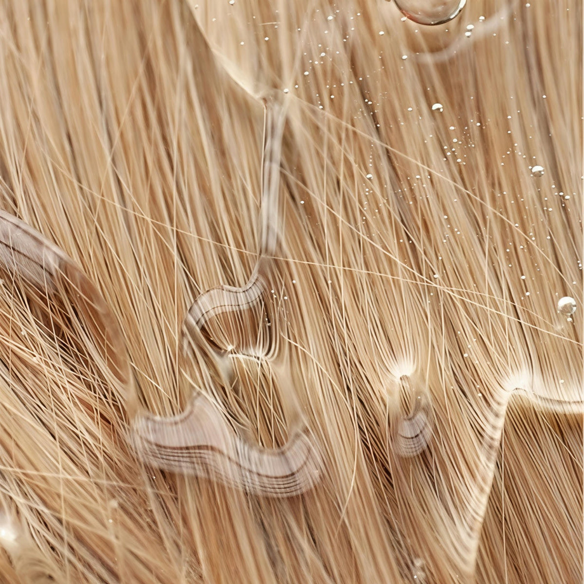 Makroaufnahme heller Haarfasern mit Wasser und glänzendem, gepflegtem Finish.